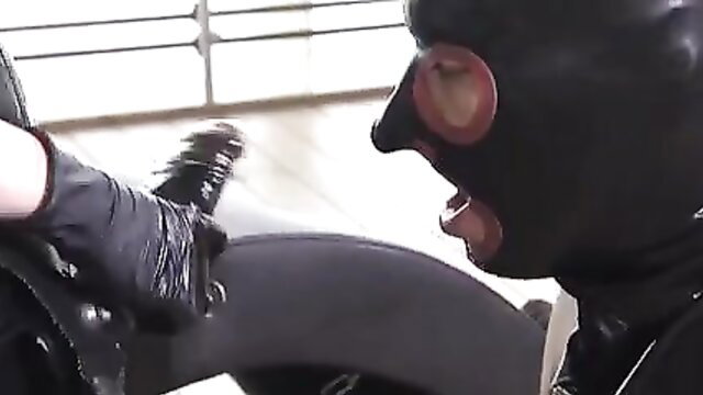 Masked man in latex mask licks black dildo on motorcycle in fetish scene