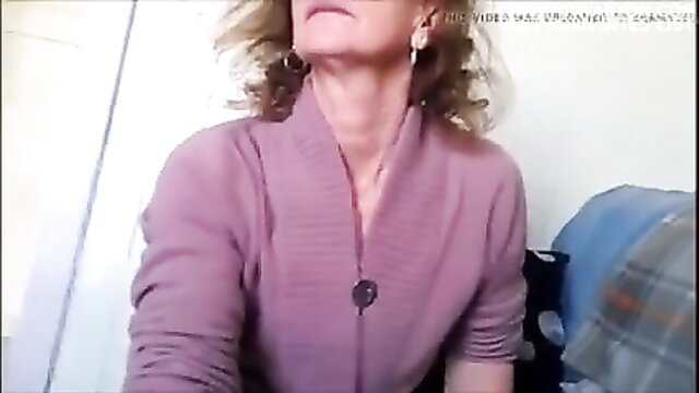 Mature blonde woman in purple cardigan watches man masturbate