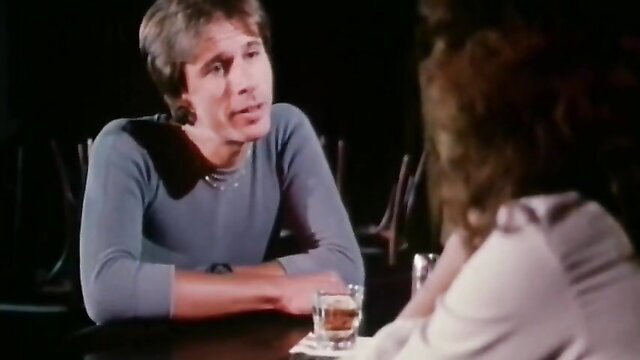 Man in sweater chats intimately with brunette woman at bar table