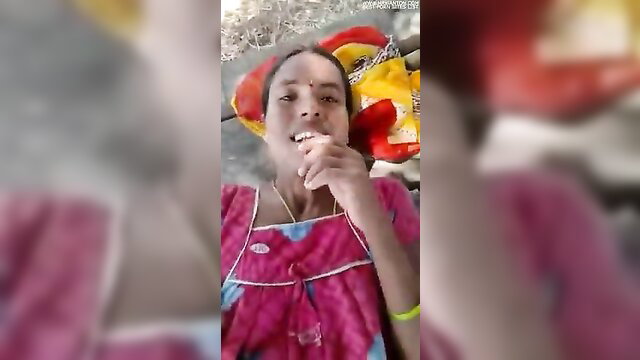 Smiling Telugu Indian woman in pink nightie licking finger outdoors