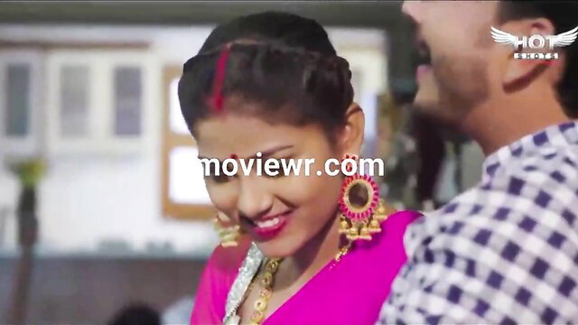 Indian beauty in pink saree with big jhumkas smiles seductively at man