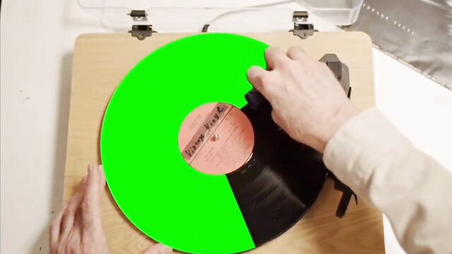 Husband's friend hand on green half vinyl record on turntable