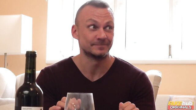 Bald white man sips wine smirking at camera in Fake Hub scene