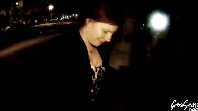 Redhead in black top with deep cleavage smiles in dark car at night