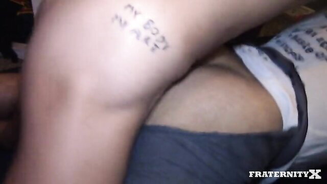 Frat X twink with 'FUCK YOUR DUES' tattoo on thigh in jockstrap