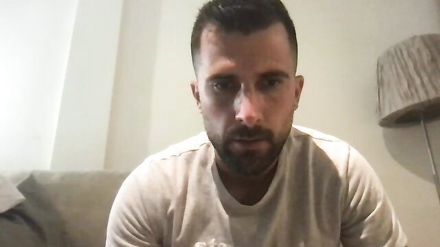 Tattooed muscular man with buzzcut and beard in tight shirt, gay amateur closeup