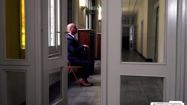 Mark Aurel in suit seated in office, tense anticipation