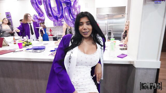 Diabella Eclair in cleavage-baring white dress and purple graduation gown