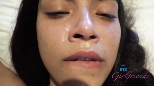 Closeup of aroused Asian beauty with glossy lips and sweaty face in bed