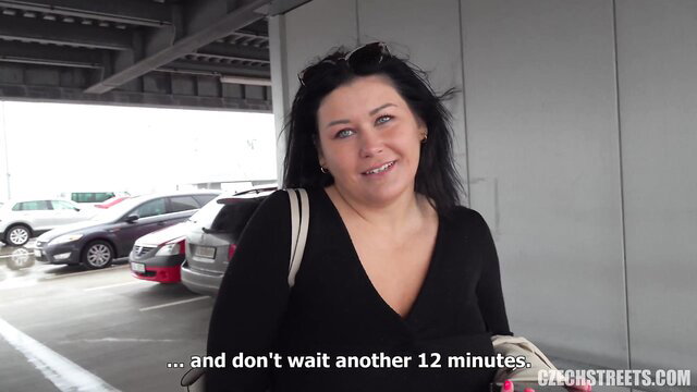 Busty married brunette MILF smiling in car park, black top tease