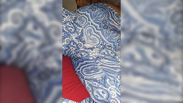 Curvy black woman in tight blue paisley dress on bed