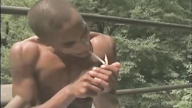 Muscular black man nude smoking joint closeup in outdoor adult video