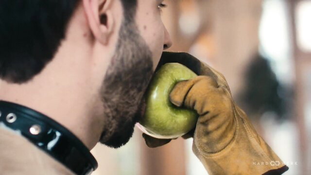 Eden Ivy biting green apple in leather collar and work gloves closeup