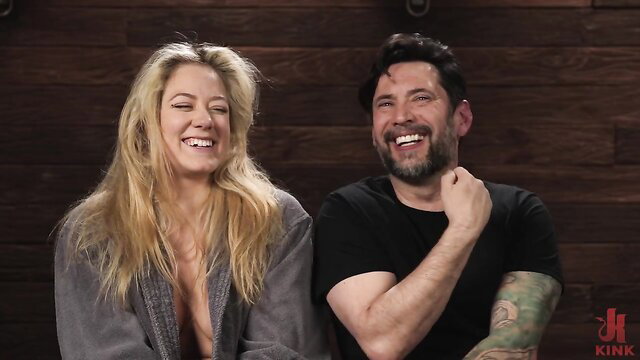 Blonde River Lynn smiles with bearded man in Kink.com DungeonSex scene