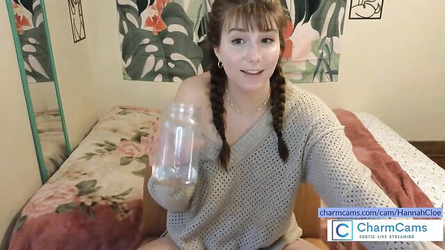 Hannah Cloe holds jar in cozy bedroom, off-shoulder sweater, pigtails