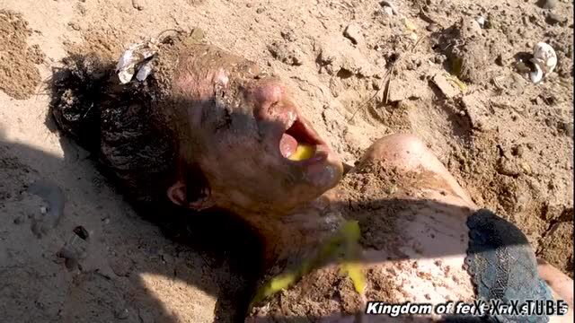Muddy woman buried in sand with mouth open, extreme fetish scene