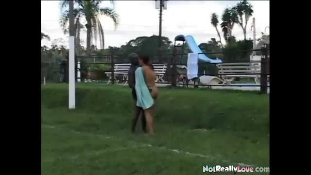 Interracial couple standing on grass near playground