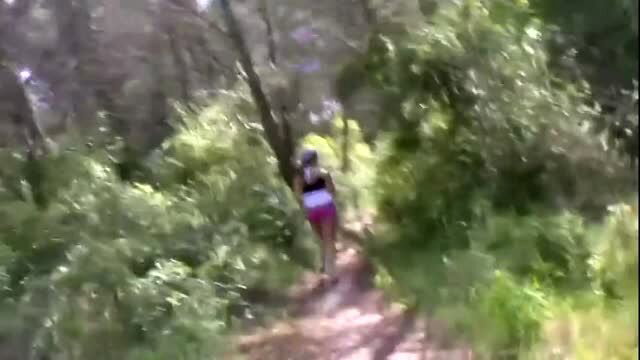 Woman in pink shorts hiking on forest trail outdoors