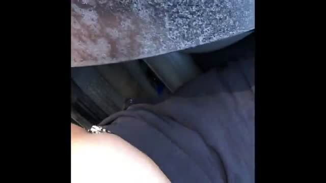 BBW MILF in dark clothing sitting under a vehicle