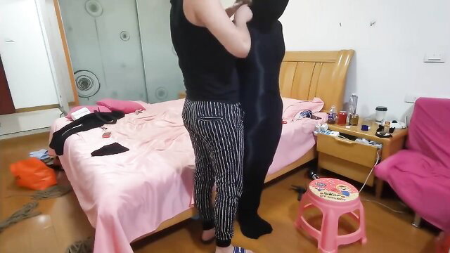 Woman in black pantyhose embraced from behind in BDSM encasement fetish