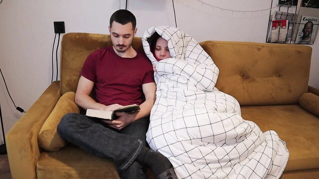 Zloy Andrey reads book to cozy hooded stepdaughter on couch