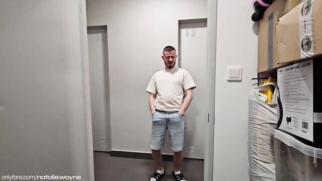 Natalie Wayne stands in hallway wearing tight white tee and shorts