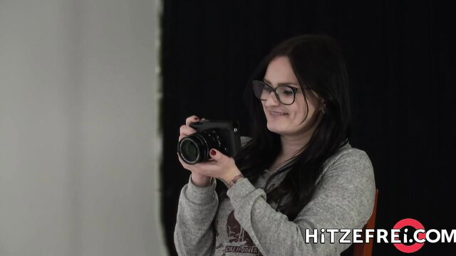 Jolee Love with big boobs holding camera, smiling in grey hoodie