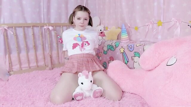 Cute blonde kiki in pink skirt spreads legs in crib with plush toys