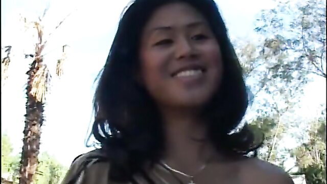 Smiling Asian beauty with long black hair in sunny outdoor setting
