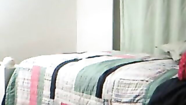 Kara in webcam chat on colorful quilt bed, casual tease