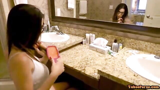 Asian MILF in white tank top applying makeup at vanity mirror