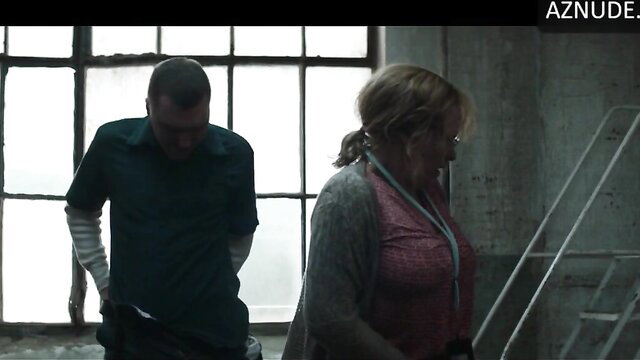 Patricia Arquette in cardigan and lanyard with man in warehouse