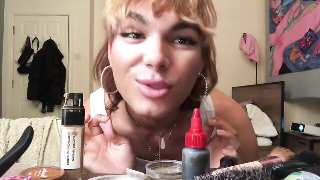 Blonde femboy with makeup holds lube bottle, throat fuck thumbnail