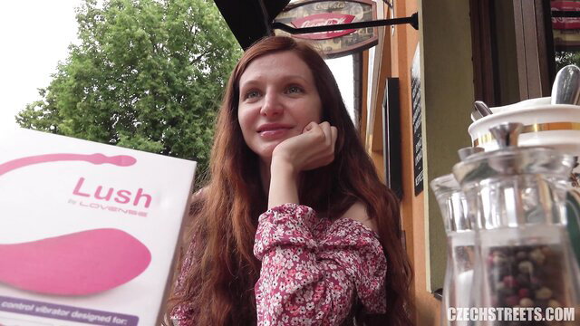Redhead with Lush vibrator in public outdoor cafe tease