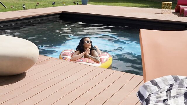 Asian ladyboy in pink donut float relaxing in pool sunglasses