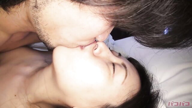 Asian couple passionately kissing in bed, intense foreplay