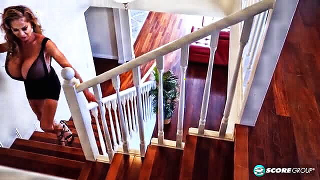 Minka in tight black dress walks upstairs, huge tits bursting out