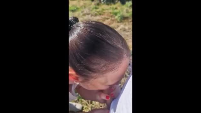 Woman kneeling outdoors receives facial cumshot during walk