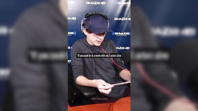 Tom Holland in black cap and headset at Shada4 event, mic in hand