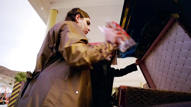 Rihanna in sexy raincoat bending over trunk in Bitch Better Have My Money video