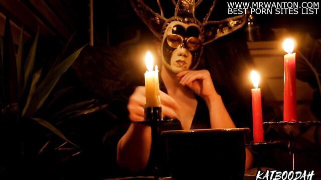 Goddess Katboodah in ornate mask holds candles at abundance ceremony