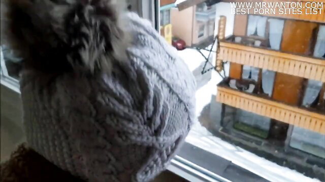 Winter tease: fluffy sweater girl at window overlooking snowy chalets