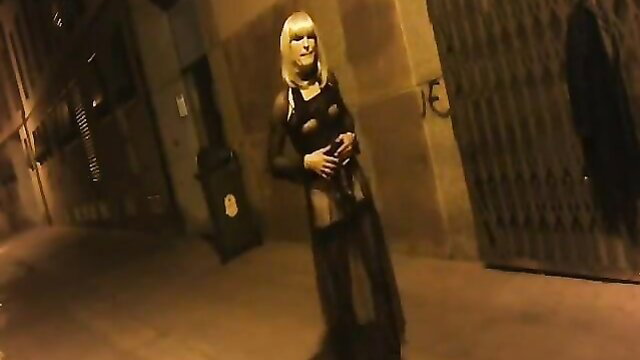 Blonde in sheer black lingerie exhibits in dark urban alley night