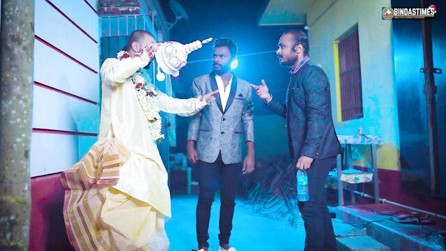 Indian groom in dhoti with suited men at desi wedding night party