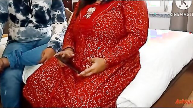 Woman in red dress holding phone, sitting with man