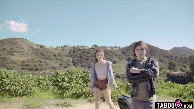 Liz Jordan & Reagan Foxx as teen hitchhikers in shorts outdoors
