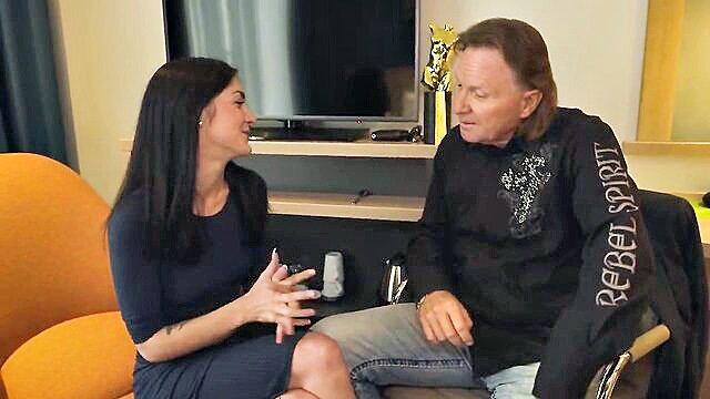 Brunette in tight dress interviews rockstar in casual interview