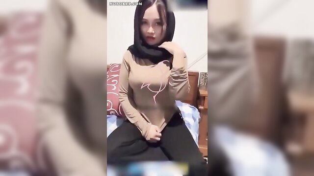 Hijab babe in tight top and pants sits seductively on bed