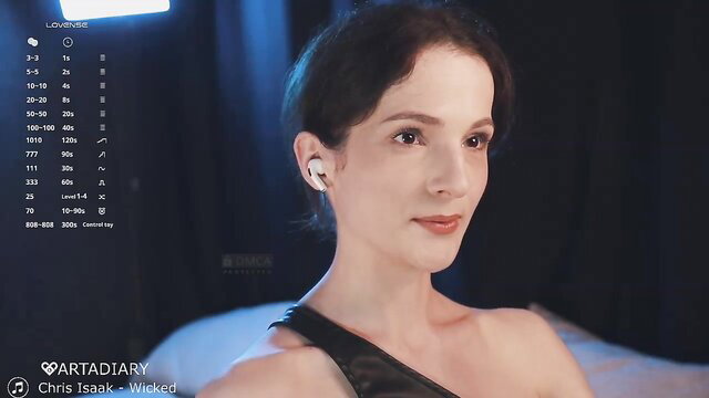 Closeup of seductive brunette in black dress with AirPods, sultry gaze