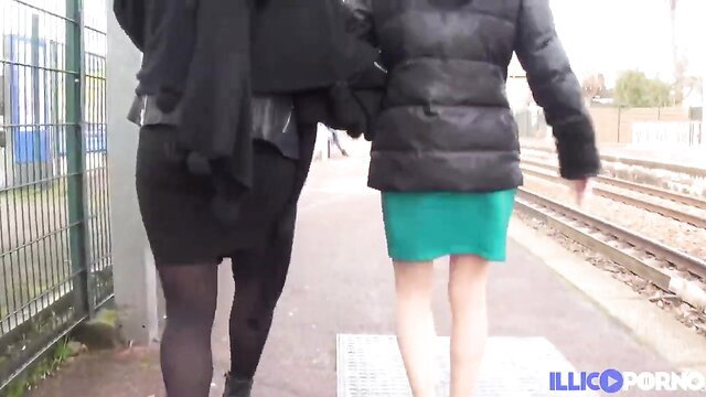 Two beautiful lesbians in skirts and coats walking on outdoor train platform